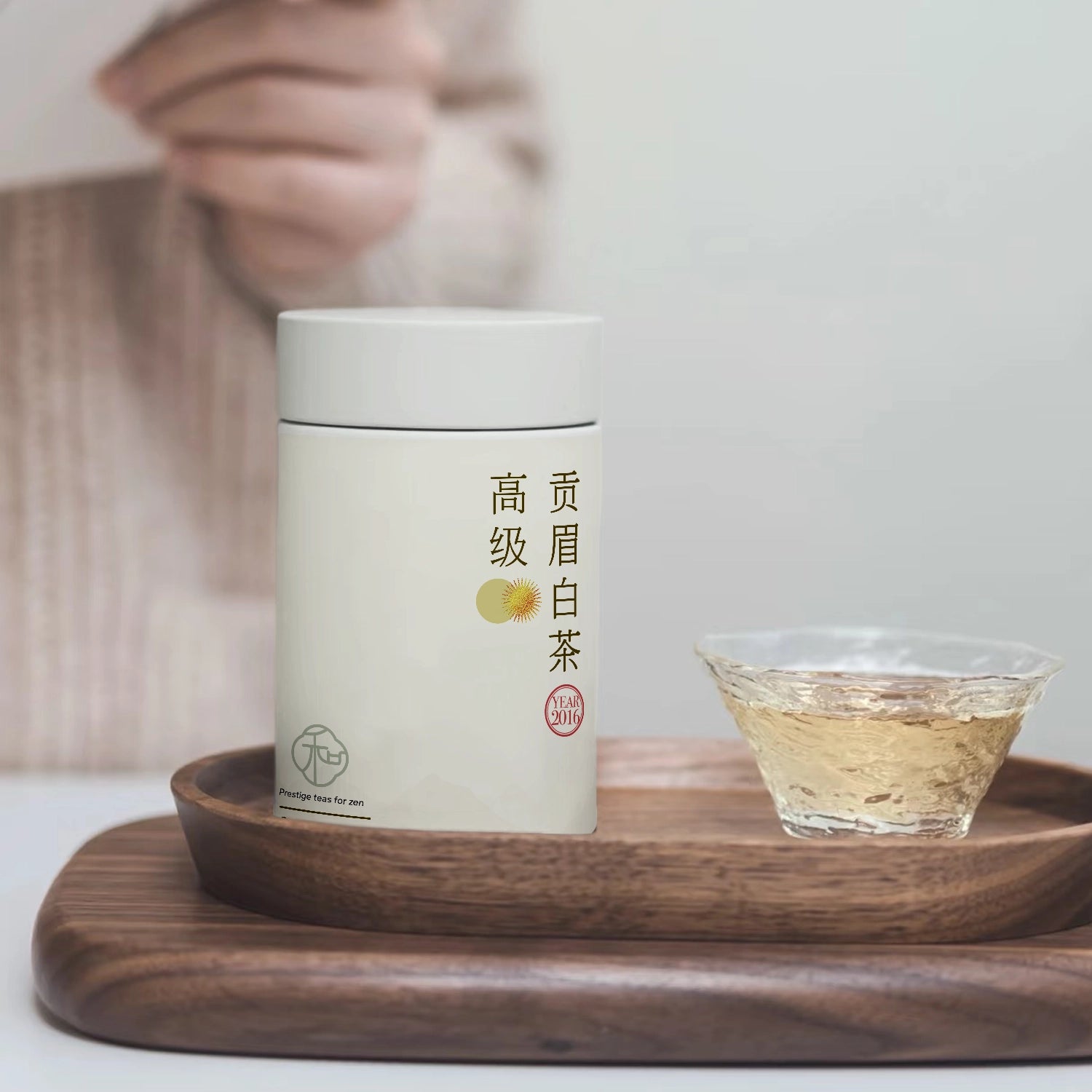a lifestyle photo of a single tea tin of luxury chinese gaojigongmei loose white tea packaged in branded elegant white tea tin with a single cup of white tea in a textured cup